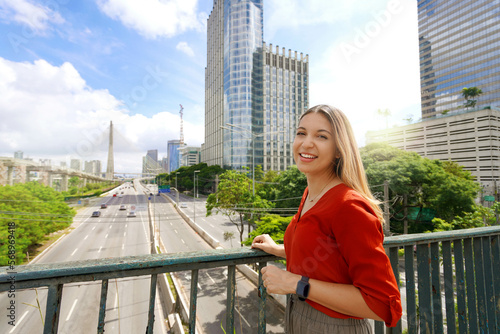 Travel in Sao Paulo, Brazil. Portrait of beautiful smiling girl with Sao Paulo cityscape and Ponte Estaiada bridge on the background, Sao Paulo, Brazil. photo