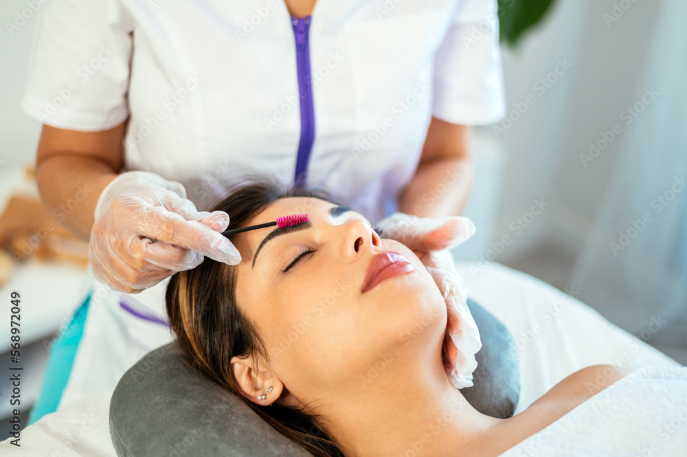 Crop beautician brushing eyebrows of female client Crop beautician brushing eyebrows of female client
