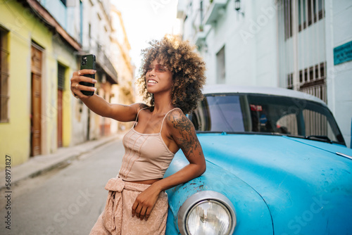 Cuban woman taking selfie near retro car photo