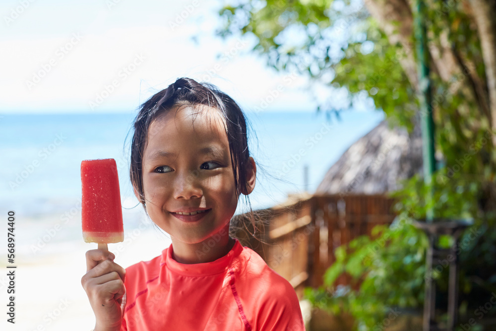 Asian girl happily eating her favorite watermelon popsicle Asian girl happily eating her favorite watermelon popsicle