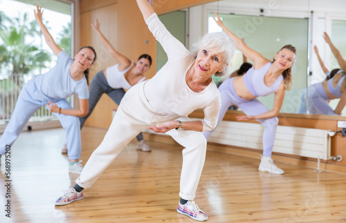Active aged woman practicing fitness dance in training hall during dancing-classes. Women training dance in hall © JackF
