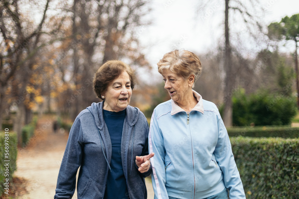 Two senior women in sportswear walking and exercising in a park Two senior women in sportswear walking and exercising in a park