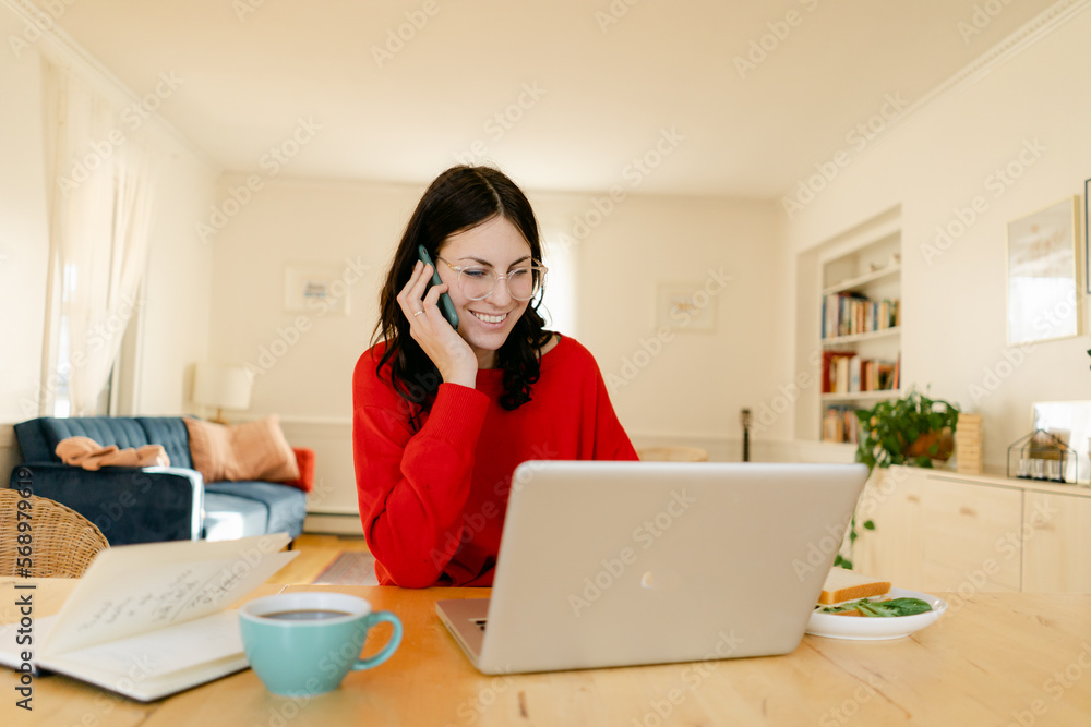 smiling woman on phone while on laptop smiling woman on phone while on laptop