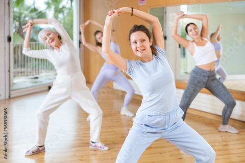 Active middle-aged woman practicing aerobic dance in training hall during fitness dance classes. Women training dance in hall