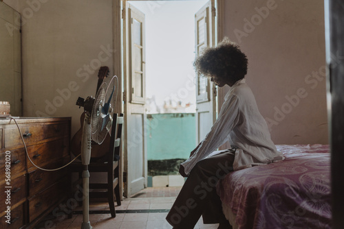 Cuban woman sitting on bed at home