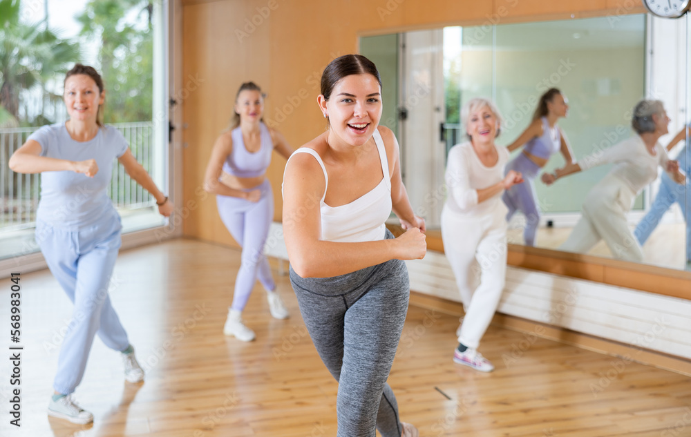 Fototapeta premium Active young woman practicing aerobic dance in training hall during fitness dance classes. Women training dance in hall