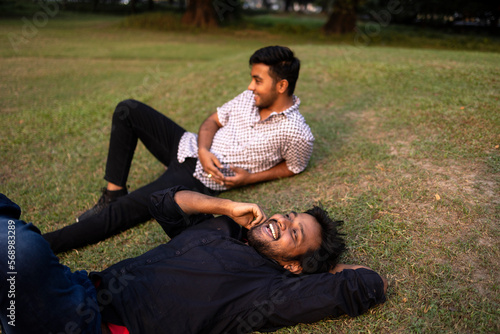 Two friends relaxing and interacting lying on grass ground photo