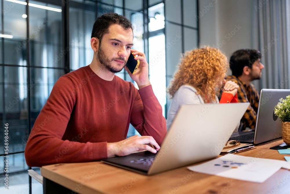 Cheerful man talking on smartphone in a modern office Cheerful man talking on smartphone in a modern office