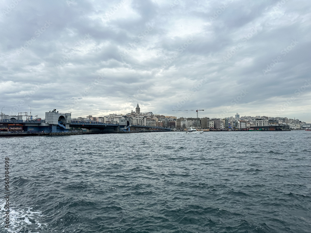 Istanbul, Turkey. Karaköy,Istanbul with Galata tower, Galata bridge and architecture on cloudy day. Scenic view of Karakoy quarter and Galata Tower from Golden Horn Bay in winter twilight