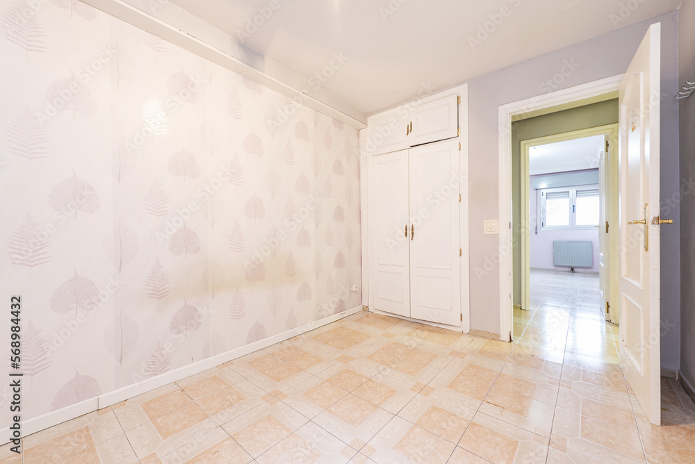 old room with papered walls and built-in wardrobe with white doors and two-tone tiles