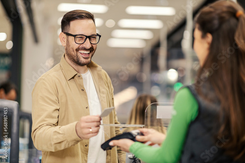 Obraz na plátně A happy man on checkout is paying with credit card on pos terminal