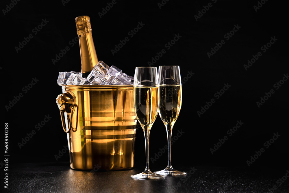 Two glasses of champagne and a bottle in a golden bucket with ice on a black background