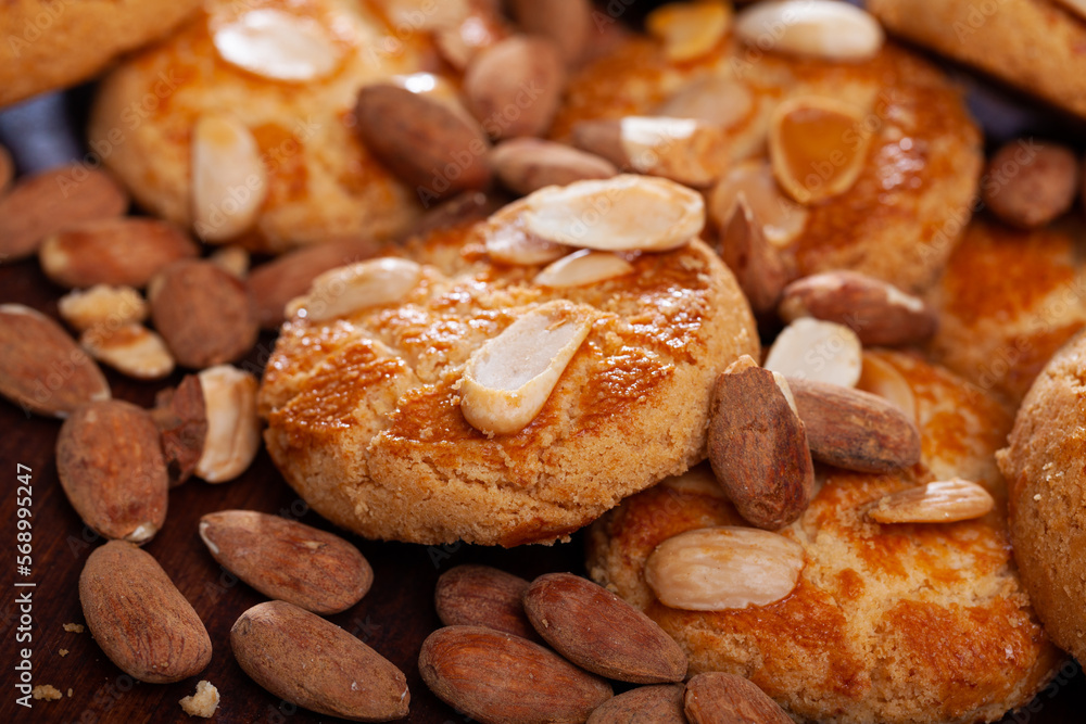 Pile of shortbread almond biscuits and nuts on wooden surface ..