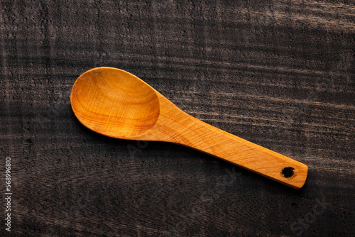 Wooden spoon, kitchen utensil on dark rustic background