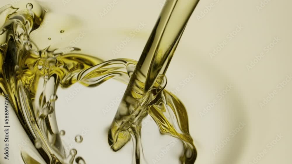 Macro crane shot of almond oil is being poured into pale yellow oil on white background | Abstract skin care cosmetics ingredients formulating concept Macro crane shot of almond oil is being poured into pale yellow oil on white background | Abstract skin care cosmetics ingredients formulating concept