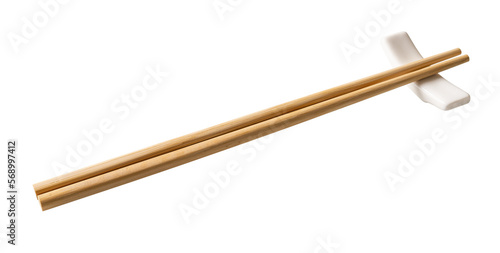 Wooden chopsticks on a white chopstick rest cutout. Pair of bamboo chopsticks on a porcelain holder  isolated on a white background. Japanese, Chinese, East Asian tableware concept.