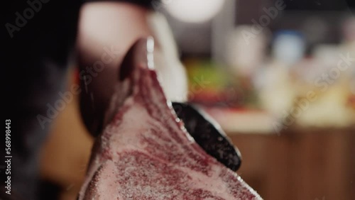 Beautiful piece of prime rib being seasoned and carefully placed on the barbecue fire photo