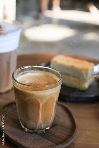 Dirty coffee with cake in coffee shop cafe and restaurant. Cold milk topped with hot espresso shot. on wooden table.