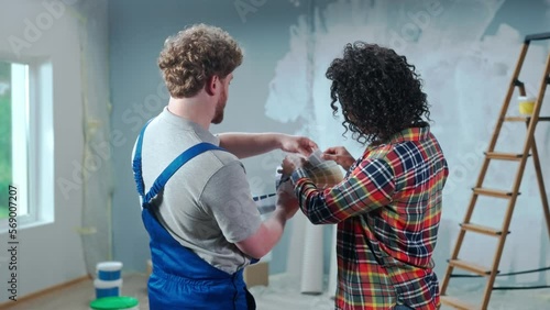 Customer is an African American woman and white male foreman choosing paint color on color palette. Female discussing color of wall painting with master during renovation of apartment, rear view. photo