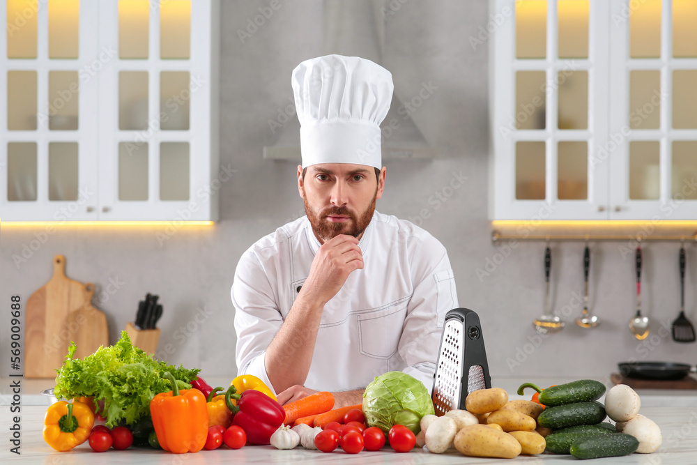 Portrait of thoughtful chef near vegetables at table in kitchen Portrait of thoughtful chef near vegetables at table in kitchen