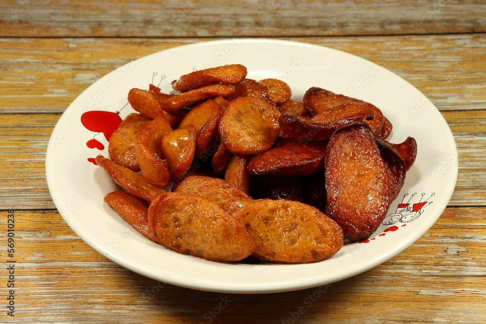 Traditional deep fried pork sausage serving on the plate. Famous roasted and grilled sliced meat menu in Asian restaurant. Traditional deep fried pork sausage serving on the plate. Famous roasted and grilled sliced meat menu in Asian restaurant.