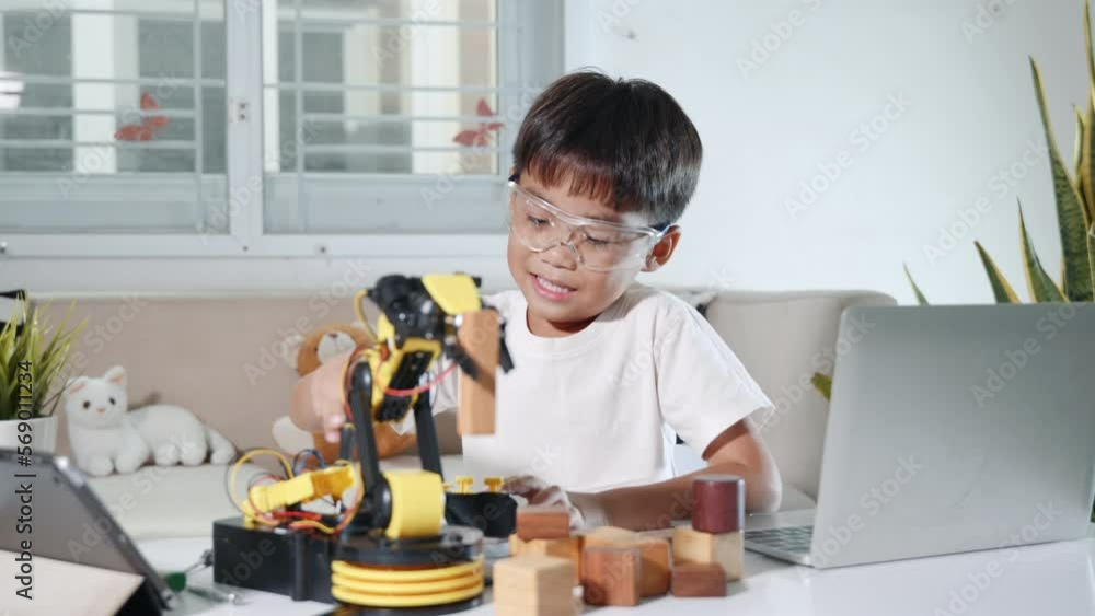 Happy Asian little kid boy using screwdriver to fixes screws robotic machine arm in home workshop, child learning repairing get lesson control robot arm, Technology future science education concept Happy Asian little kid boy using screwdriver to fixes screws robotic machine arm in home workshop, child learning repairing get lesson control robot arm, Technology future science education concept