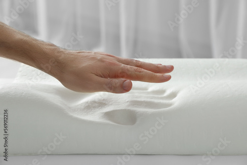 Man with orthopedic memory foam pillow indoors, closeup