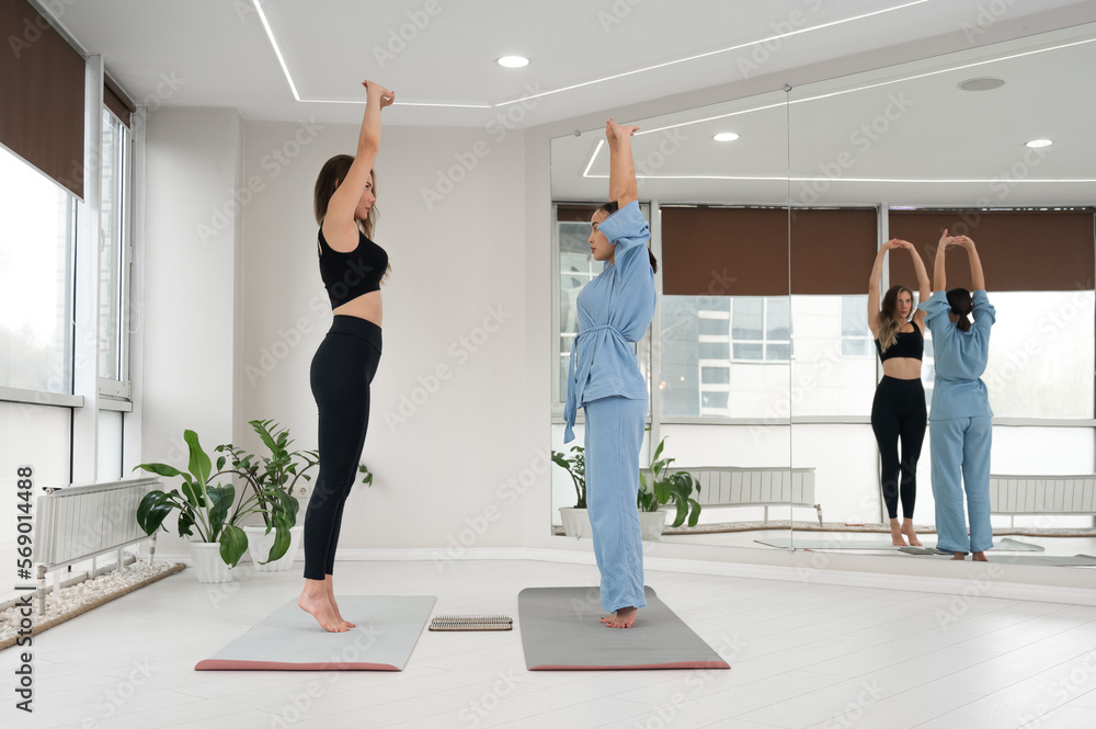 Fototapeta premium Caucasian and Asian women getting ready to stand on sadhu boards.