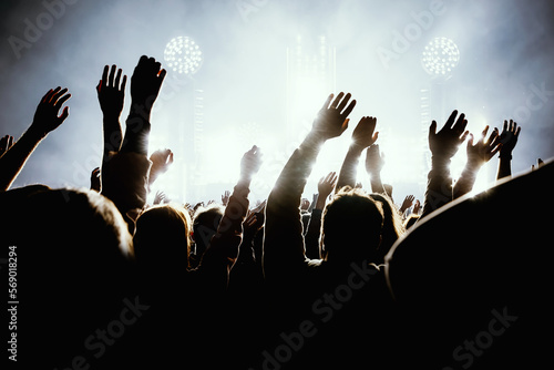 Silhouette of a happy crowd with hands up during a big rock concert.
