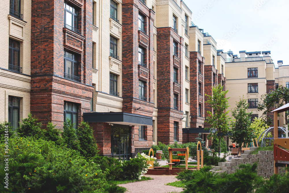 Fototapeta premium Modern european residential apartment complex yard territory, multi-story house buildings with playground and benches, contemporary scandinavian housing development, facade exterior and courtyard