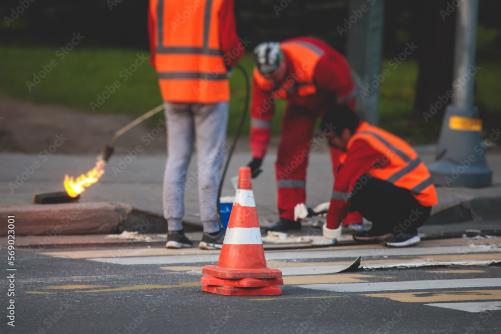 Process of making new road surface markings with a line striping machine, workers improve city infrastructure, demarcation marking of pedestrian crossing with hot melted paint on asphalt pavement Process of making new road surface markings with a line striping machine, workers improve city infrastructure, demarcation marking of pedestrian crossing with hot melted paint on asphalt pavement