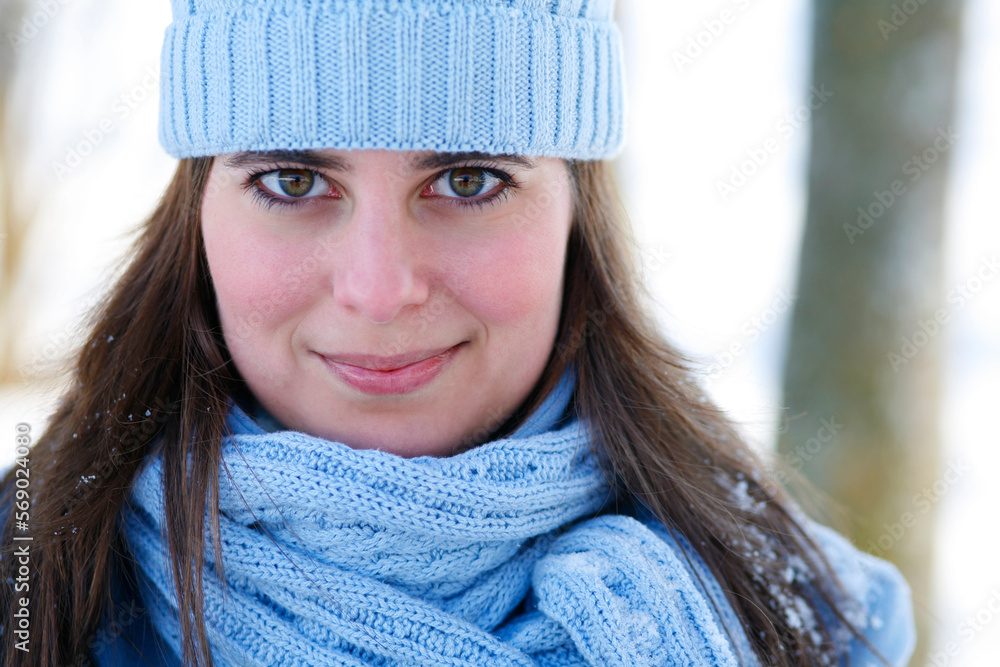 Attractive young woman outdoors in winter wearing blue knit hat and looking at camera. Attractive young woman outdoors in winter wearing blue knit hat and looking at camera.