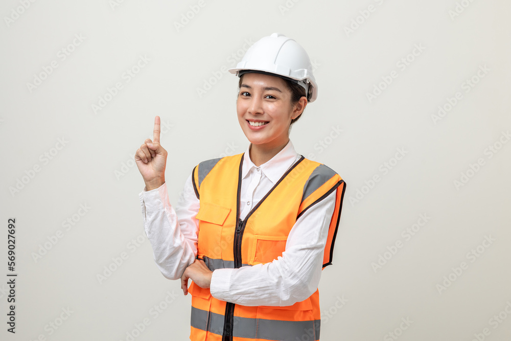 Asian engineer worker woman or architect with white safety helmet standing on isolated white background. Mechanic service factory Professional work job occupation in uniform pointing finger to space