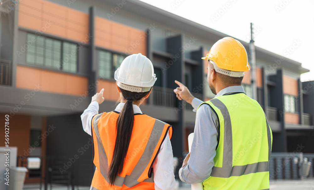 Two Asian worker engineer architect man and woman architect looking construction with white safety helmet in modern home building construction. Work planning with blueprint and tablet. Two Asian worker engineer architect man and woman architect looking construction with white safety helmet in modern home building construction. Work planning with blueprint and tablet.