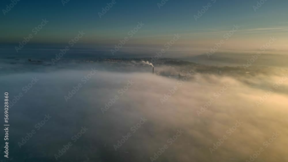Aerial Drone scene above the Urban townscape area shrouded In thick morning mist. Warm morning sunlight. Abovet the clouds Aerial Drone scene above the Urban townscape area shrouded In thick morning mist. Warm morning sunlight. Abovet the clouds