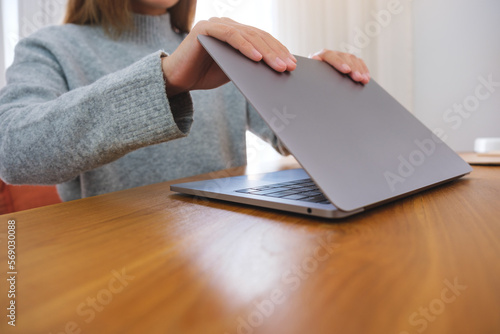 Closeup image of a woman closing or opening a laptop computer on table after finished using it photo