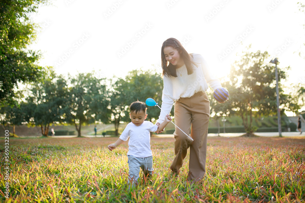 Happy Asian mother and son playing on lawn in the park on a holiday, the family having fun and spending time together, Happy family concept. Happy Asian mother and son playing on lawn in the park on a holiday, the family having fun and spending time together, Happy family concept.