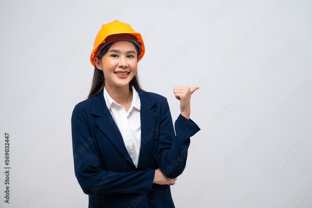 Portrait of Asian female engineer with hard hat posing show thumb up like gesture isolated on grey background.
