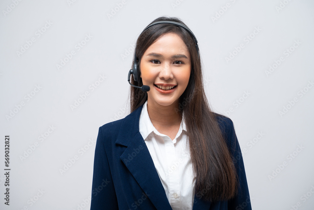 Beautiful Asian call center operator wearing a headset and microphone standing with her arms crossed isolated on grey background. Beautiful Asian call center operator wearing a headset and microphone standing with her arms crossed isolated on grey background.