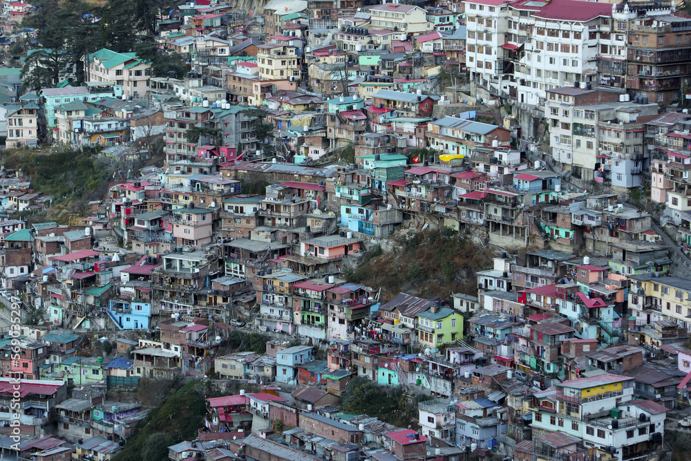 Many houses on a densely populated hillside in Shimla Northern India. House in the foothills of the Himalaya mountains capital of Himachal Pradesh. Ariel view of Shimla town.