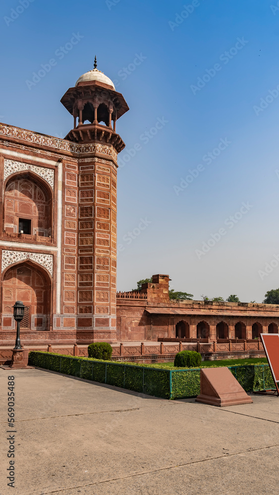 A fragment of the ancient Kau Ban Mosque in the Taj Mahal complex. The red sandstone building is decorated with white marble with inlays and ornaments. Nearby - a gallery with arches and columns.India