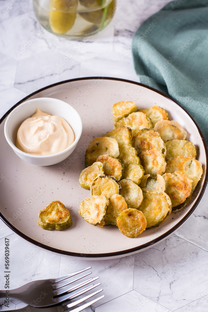 Fried pickles appetizer and sauce in a bowl on a plate. Homemade snack. Vertical view