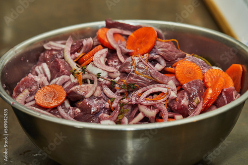 Diced beef with onions and carrots in metal bowl ready for cooking