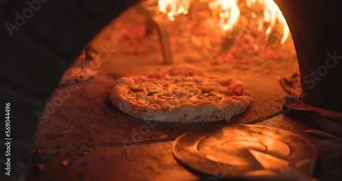 Baking the smoking hot delicious pizza in a traditional Italian oven with wood fire flame. Spin and turn, pull in and pull off in slow motion. 