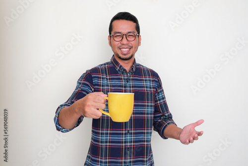 Adult Asian man smiling happy while offering a glass of drink photo