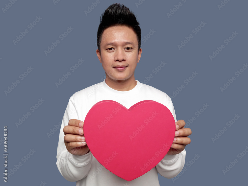 Handsome man holding and showing red heart shape with both hands Handsome man holding and showing red heart shape with both hands