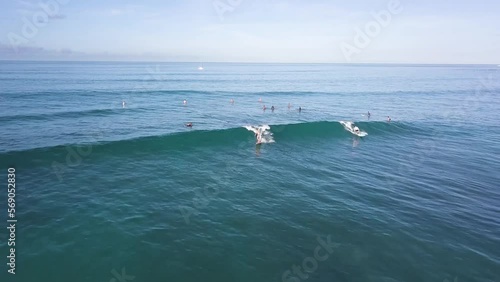 Two surfers aggressively shredding a wave on the beautiful waters of waikiki beach in honolulu hawaii, AERIAL DOLLY PULLBACK photo