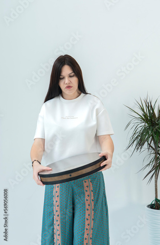 A young woman, a brunette with long hair, holds a tambourine (ocean drum) in her hands. High quality photo photo