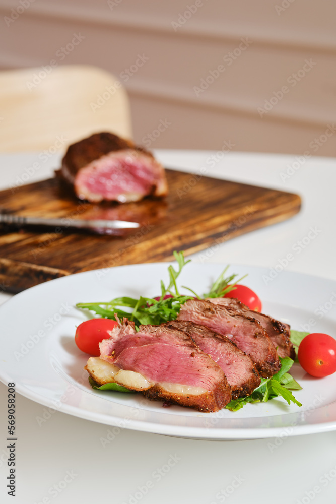 Juicy fried duck breast served on a plate with fresh arugula and corn salad