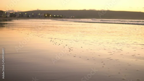 Foam from the seashore on wet sand, at sunset. Slow motion shot. Barbate, Cadiz, Spain photo